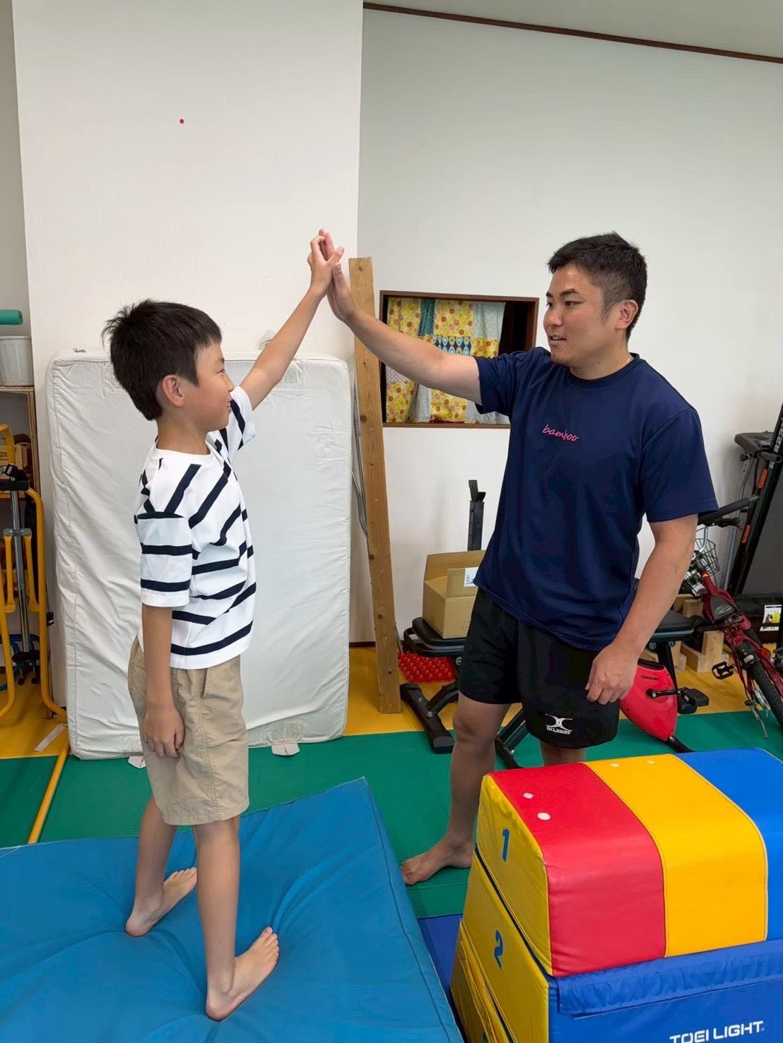 運動を終えてスタッフとハイタッチをするお子さま