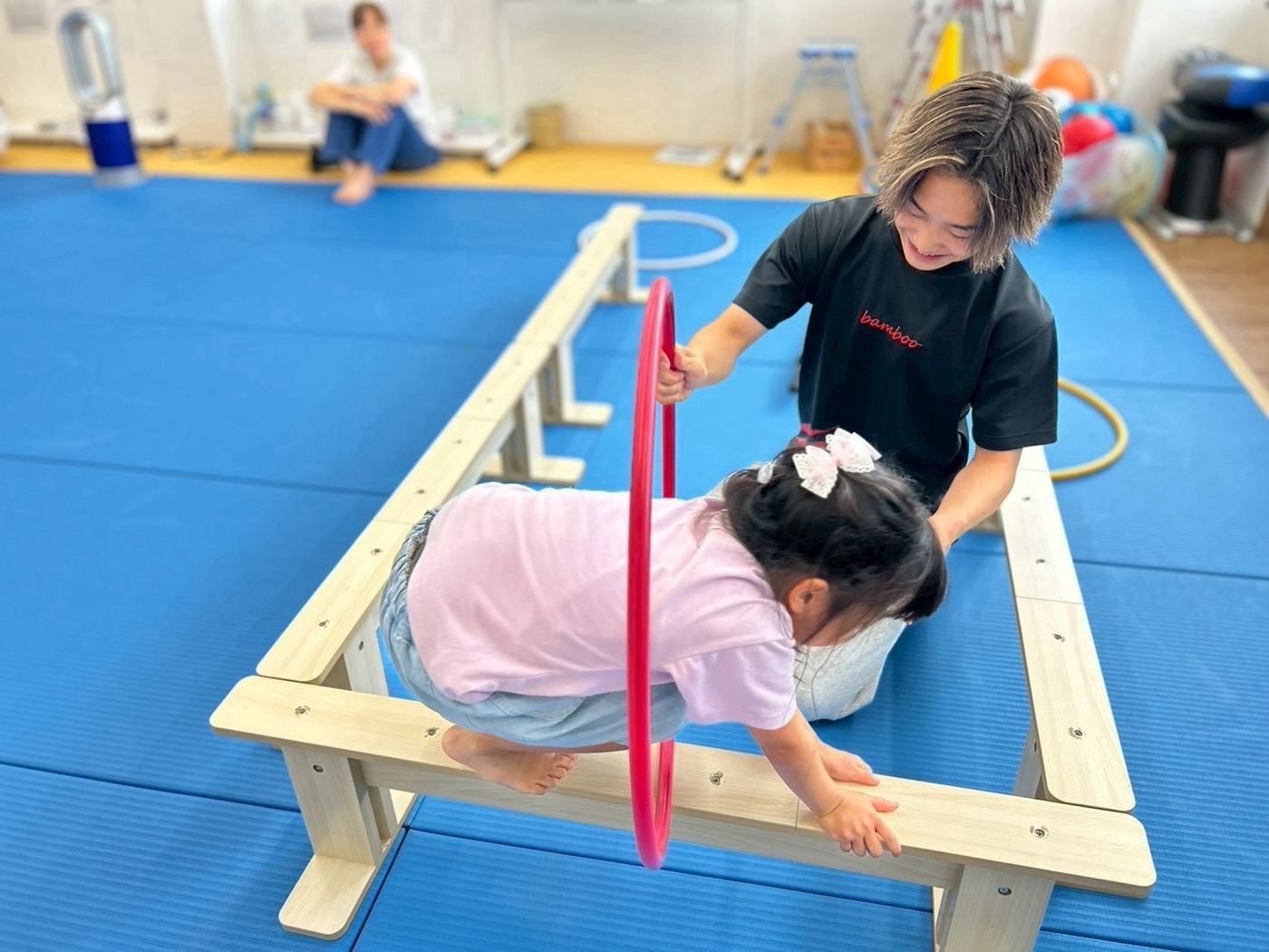 平均台の運動をサポートするスタッフとお子さま