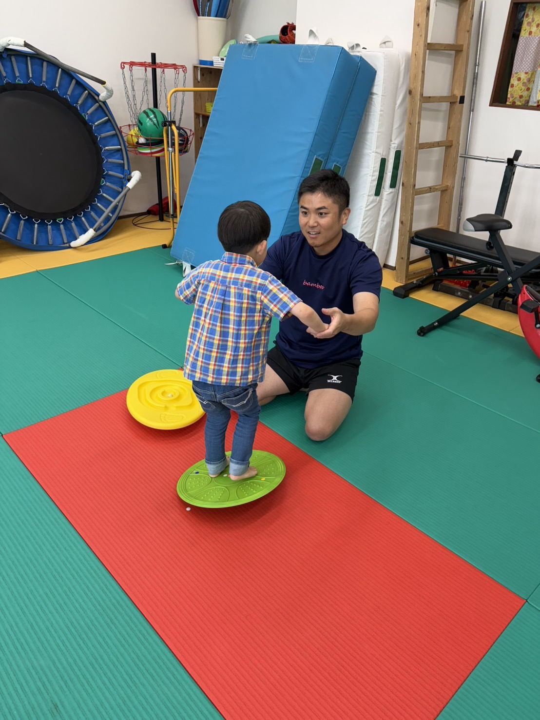 バランスボードで体幹を鍛えるお子さまとスタッフ